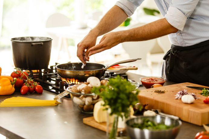 a man cooking in the kitchen at home with stainless steel pans